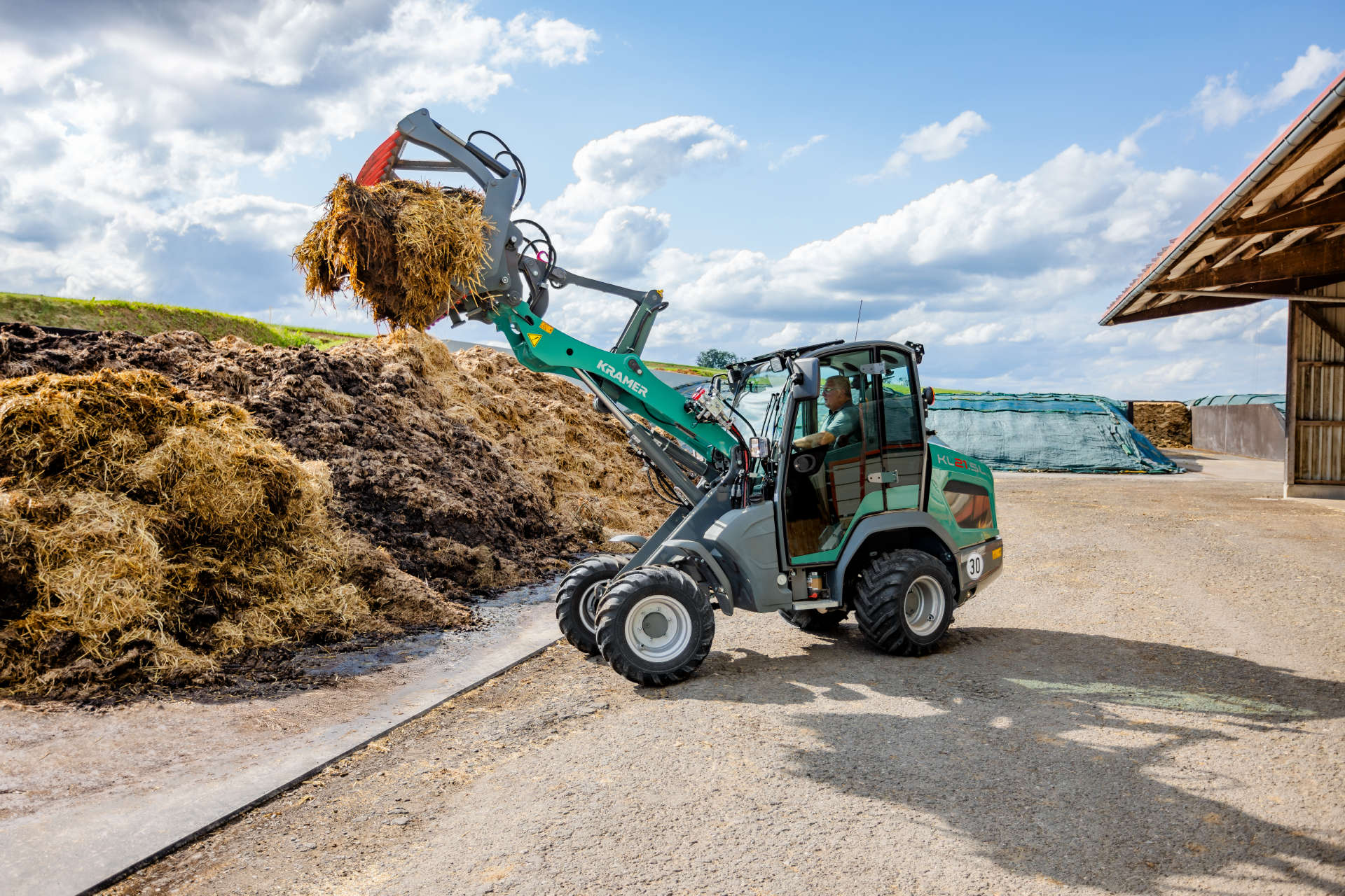 The Kramer KL21.5L wheel loader is used for working with silage in an agricultural environment.